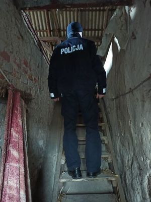 Policjant stoi na schodach opuszczonego budynku