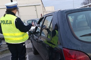 Policjantka podaje kierowcy ulotkę informacyjną