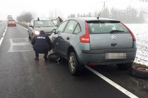 policjant zmienia koło w aucie