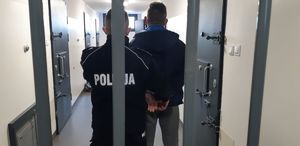policjant doprowadza do aresztu zatrzymanego sprawcę napadu