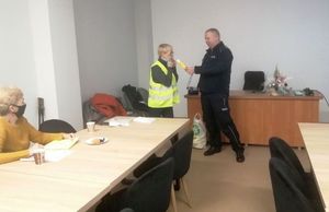 Policjant prezentuje seniorce urządzenie do badania trzeźwości