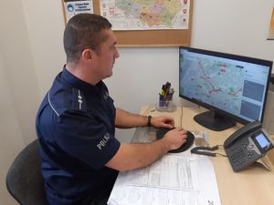 Policjant siedzi przed komputerem i KMZB