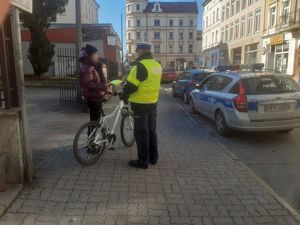 policjant wręcza kobiecie kamizelkę odblaskową