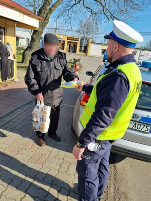 policjant rozmawia z mężczyzną i przekazuje mu kamizelkę