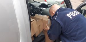 policjant pakuje do pojazdu kartony