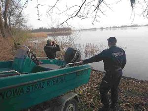 Policjant i strażnik rybacki stoi przy łodzi