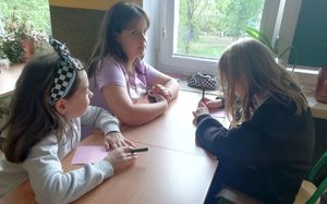 trzy dziewczynki siedzą w ławce i biorą udział w zajęciach o mowie nienawiści