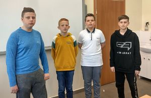czwórka uczniów stoi i bierze udział w lekcji