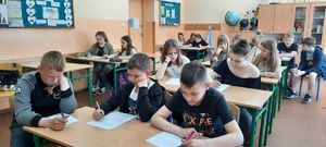 dzieci w klasie siedzą w ławkach i rozwiązują test zagadnieniowy