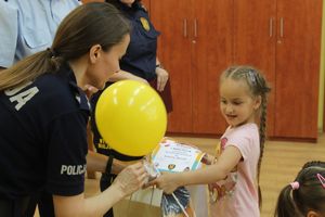 policjantka wręcza dziewczynce balonik