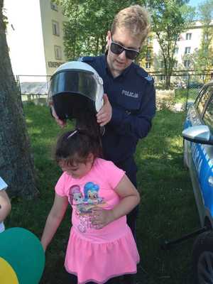 policjant zakłada dziecku na głowę hełm