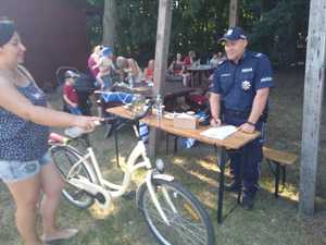 policjant z uczestnikami festyny przy stoisku