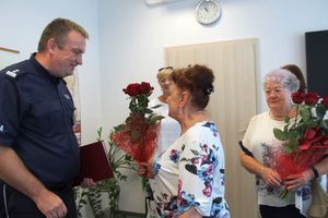 kobieta przekazuje policjantowi kwiaty