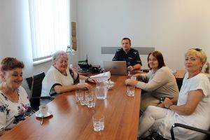 komendant i seniorki siedzą przy stola na kawie