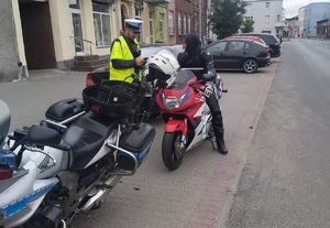 policjant drogówki stoi przy zaparkowanym motocyklu