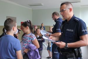 dzielnicowy przekazuje dziecku kartę z zadaniami