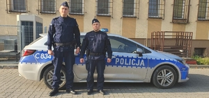 dwaj policjanci pozują przy radiowozie