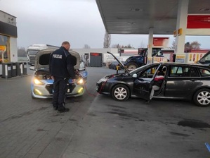 policjant na tle radiowozu i pojazdu