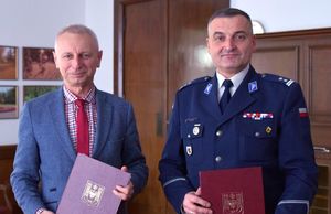 prezydent i komendant stoją i trzymają teczki z podpisanymi porozumieniami