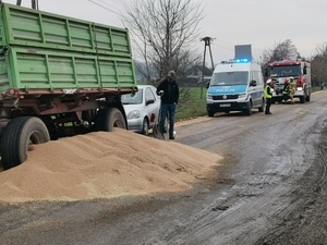 widok na ciągnik radiowóz i pojazdy oraz wysypane zboże