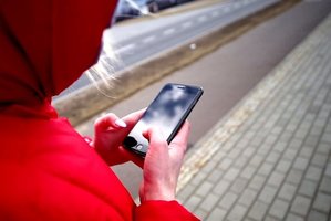 kobieta trzyma w ręku telefon i przechodzi przez ulicę