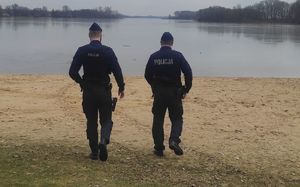 policjanci na plaży patrzą na wodę