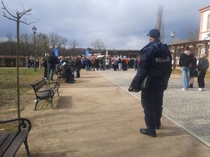 policjant patrzy na zgromadzonych ludzi