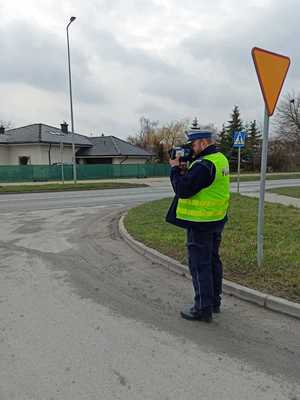 policjant mierzy miernikiem prędkości na skrzyżowaniu