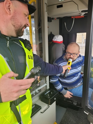 policjant sprawdza trzeźwość urządzeniem kierowcy autobusu