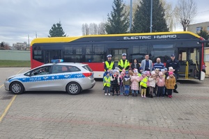 wspólne zdjęcie policjantów z dziećmi na tle autobusu. Obok stoi radiowóz