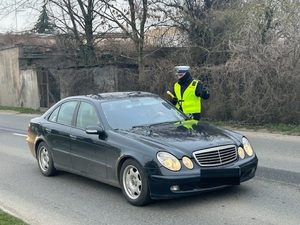 policjant przy samochodzie kontroluje kierowcę