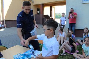 chłopiec otrzymuje od policjanta bidon