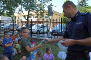 policjant wręcza dzieciom ulotki