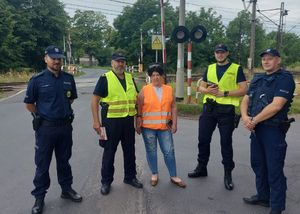 policjanci i pracownicy kolei na tle przejazdu kolejowego