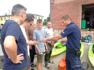 policjant wręcza młodzieży ulotki