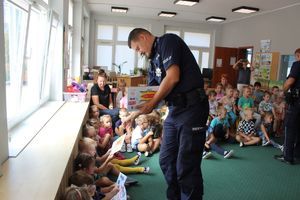 policjant wręcza dzieciom upominkik
