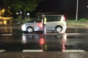 Policjant ruchu drogowego badający kierowce pojazdu osobowego.