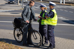 Rowerzysta oraz dwóch policjantów ruchu drogowego.