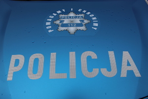 Zdjęcie maski radiowozu policyjnego z napisem pomagamy i chronimy.