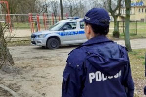 Policjant oraz w oddali radiowóz.