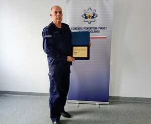 Policjant pozuje do zdjęcia, trzymając podziękowanie.