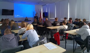 Słuchacze siedzią w ławkach w dużej sali na wykładzie policjantów