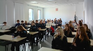 Słuchacze siedzią w ławkach w dużej sali na wykładzie policjantów