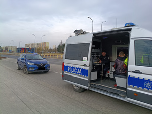 policjant wykonuje kontrolę taxi, sprawdza w radiowozie dokumenty