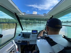 Policjant w łodzi policyjnej zabezpiecza fregaty wioślarzy na jeziorze Gopło