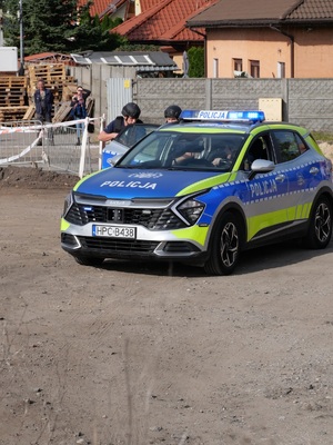 Podczas ćwiczeń: policjanci umundurowani,  długą bronią i w kamizelkach kuloodpornych przy oznakowanym radiowozie
